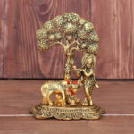 Krishna playing flute under a tree with holy cow feeding calf with milk