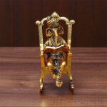 Metal Made shri Ganesh wearing pagdi and sitting on a rocking chair reading holy book ramayana